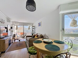 A well-lit living room with a dining table, chairs, and a sofa.