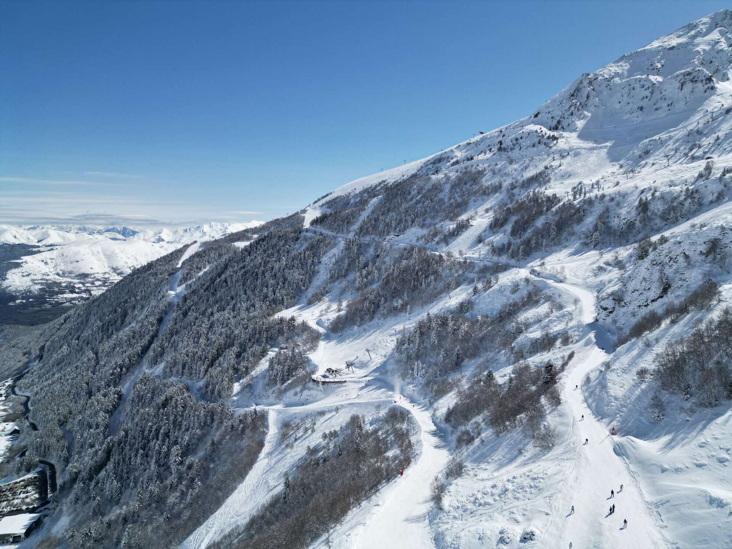 Una montagna innevata con piste da sci e un rifugio.
