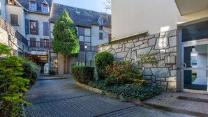 Un patio con un muro de piedra, un pequeño árbol y la entrada de un edificio con un letrero que dice "RESIDENCE LE PIC LUMIERE".