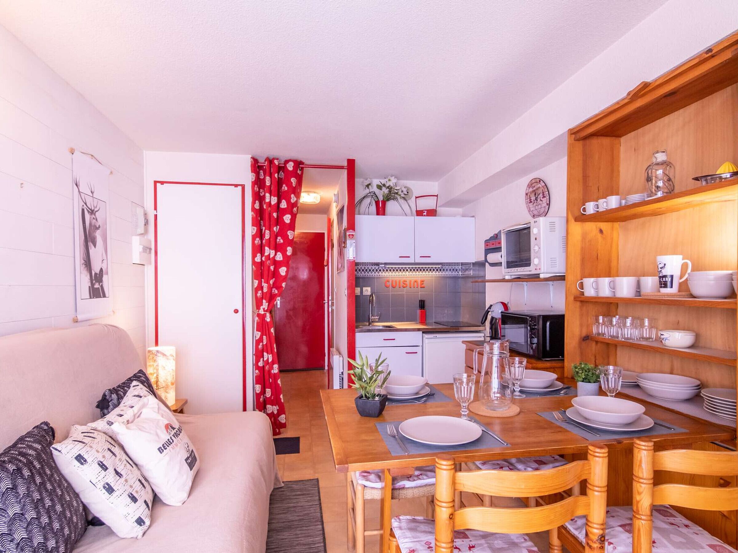 Un espacio habitable compacto con kitchenette, comedor y sofá con cojines estampados.