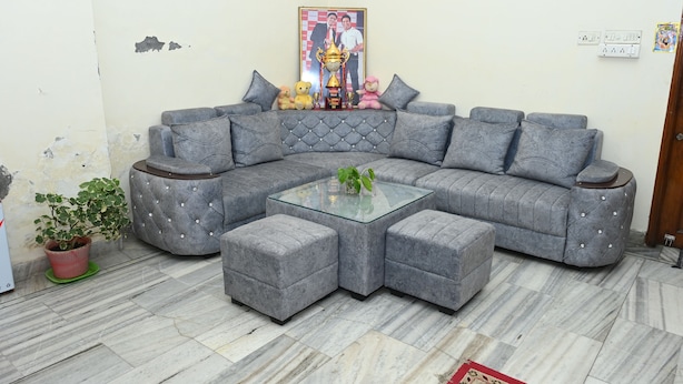 A grey sectional sofa with a glass coffee table, a potted plant, and a framed photo on the wall. - Siddhivinayak Temple Guest House (Varanasi)