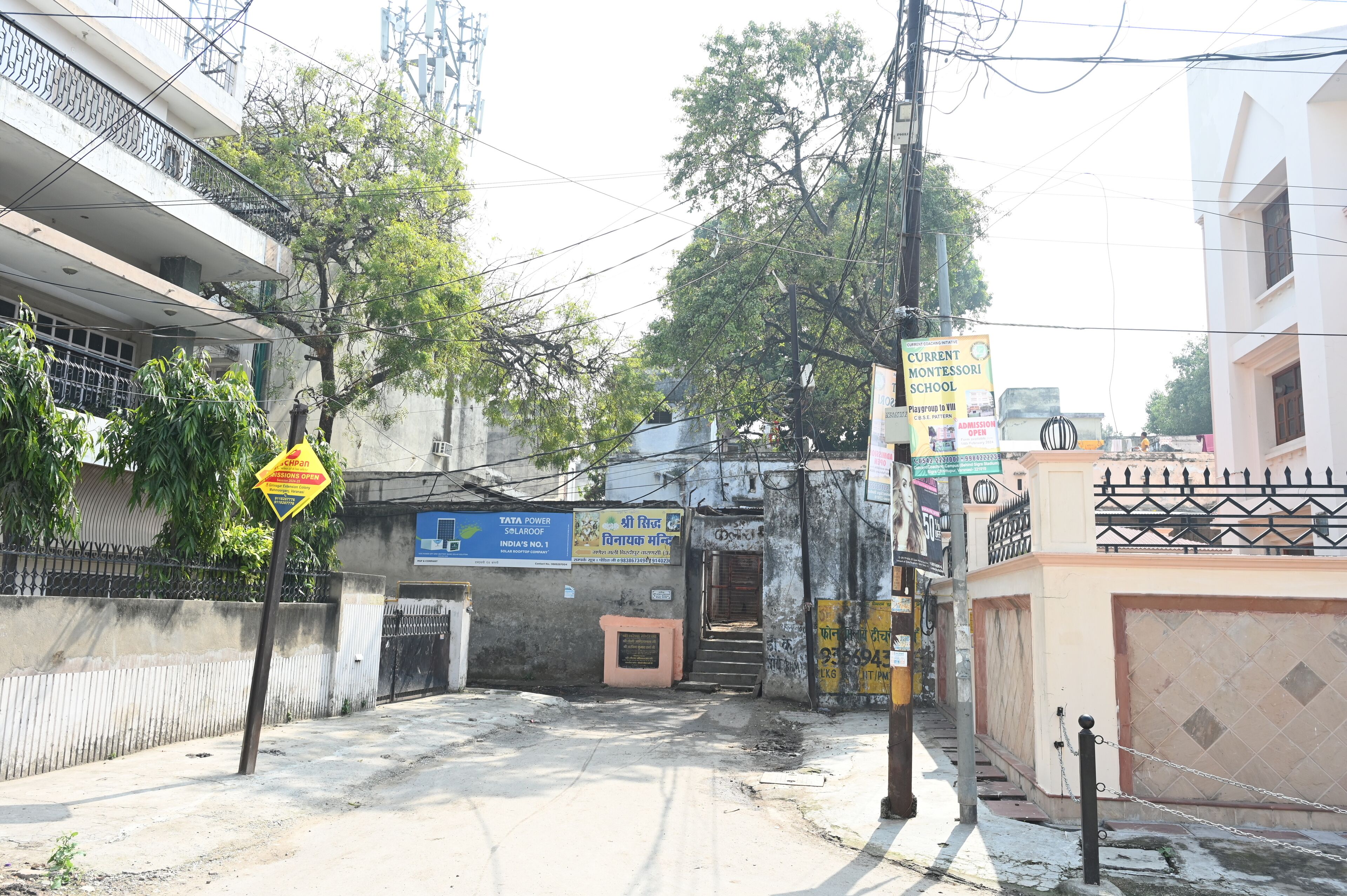 A street view with a school sign, a Tata Power sign, and a chain-link fence.