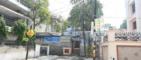 A street view with a school sign, a Tata Power sign, and a chain-link fence.