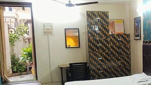 A room with a bed, a desk, a chair, and a patterned partition. - Siddhivinayak Temple Guest House (Varanasi)