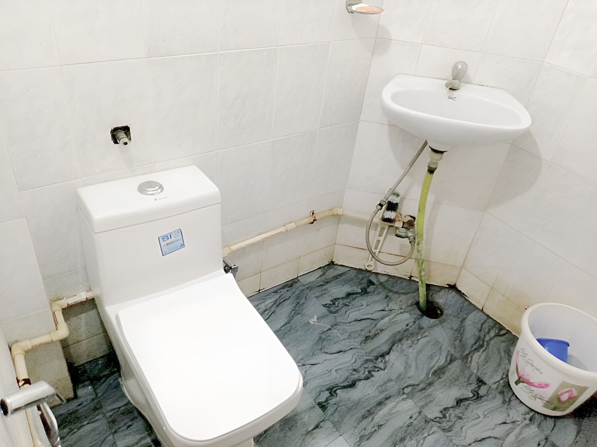 Et lille badeværelse med toilet, vask og marmorbelægning.