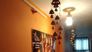 A corridor with an orange wall, a poster of a temple, and a staircase leading to a landing. - Siddhivinayak Temple Guest House (Varanasi)