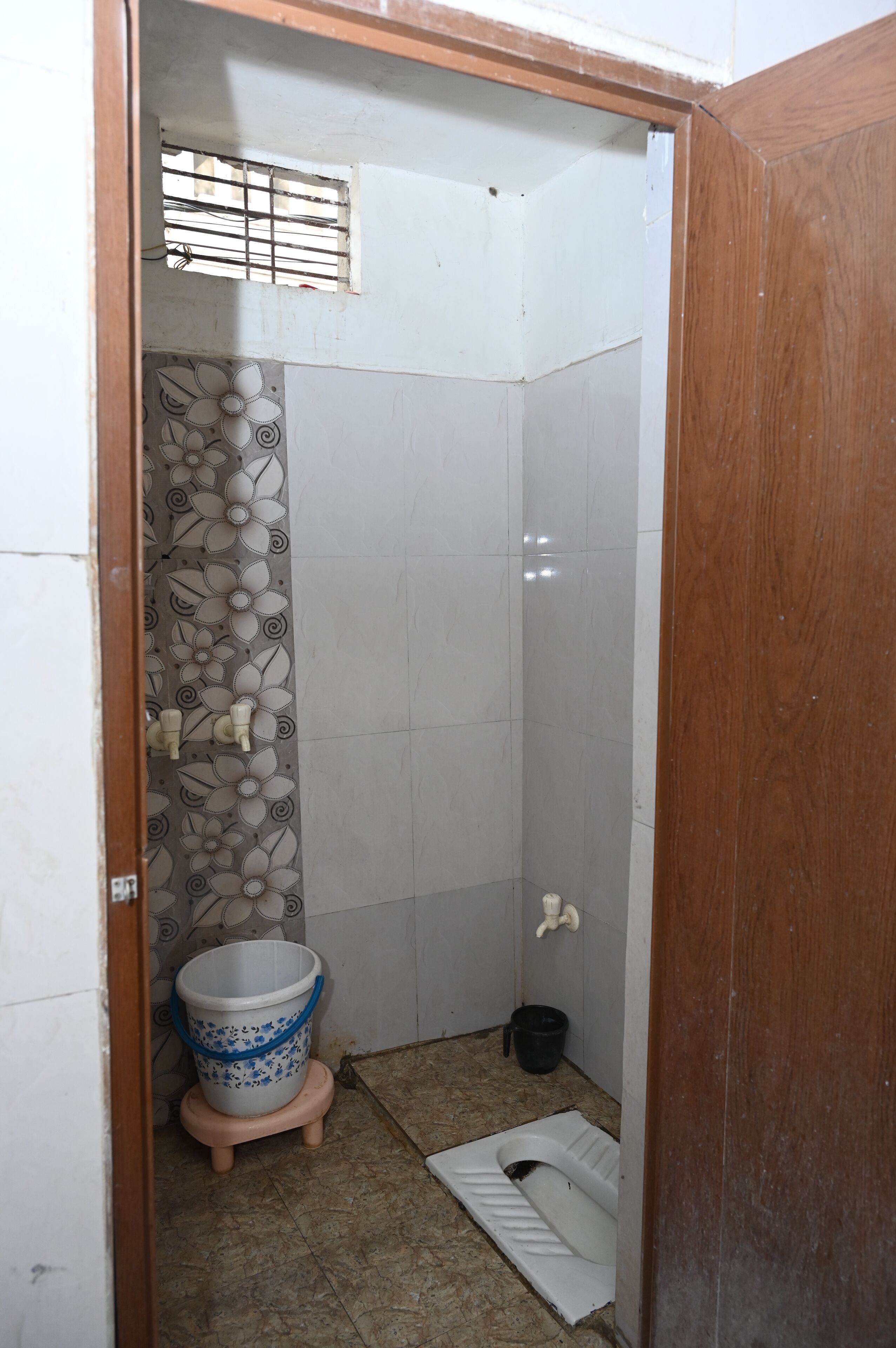 A small bathroom with a toilet, a bucket, and a shower area.