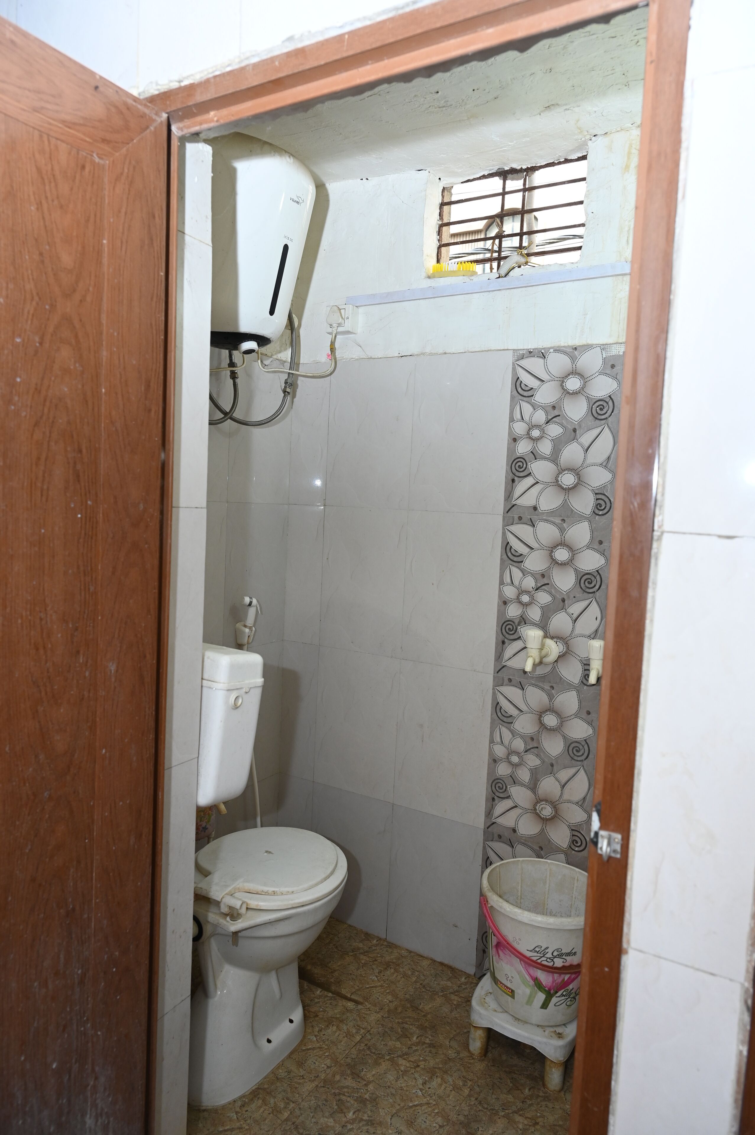Egy kis fürdőszoba, amelyben WC, zuhanyzó és vízmelegítő található.