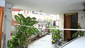 A narrow courtyard with potted plants, a metal gate, and a wooden door. - Siddhivinayak Temple Guest House (Varanasi)
