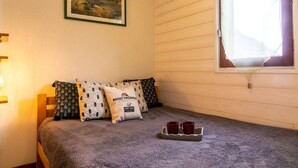 A cozy room with a bed, a framed picture on the wall, and a window with curtains. - Cozy apartment in Vielle Aure for 6 with parking (Vielle-Aure)