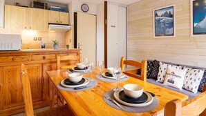 A modern kitchen with wooden cabinets, a built-in microwave, and a dining area with a wooden table set for two. - Cozy apartment in Vielle Aure for 6 with parking (Vielle-Aure)