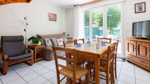 Un comedor con una mesa y sillas de madera, un sofá, un televisor y una planta.