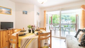 A dining area with a table set for two, a television on a cabinet, and a balcony with outdoor seating. - Apartment for 4 near thermal baths and cable car in Saint Lary (Saint-Lary-Soulan)