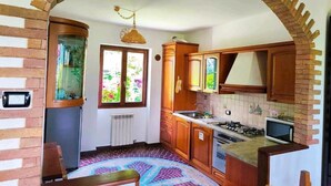 A kitchen with wooden cabinets, a gas stove, a microwave, and a window with a view of greenery.