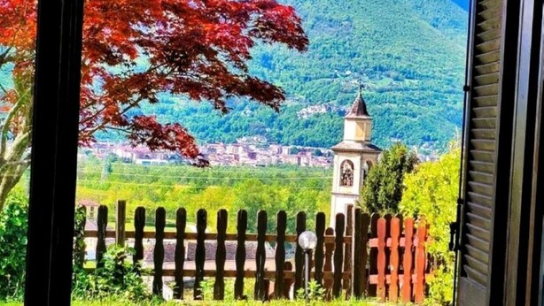 A room with a view of a mountain landscape, a wooden fence, and a small tower structure.