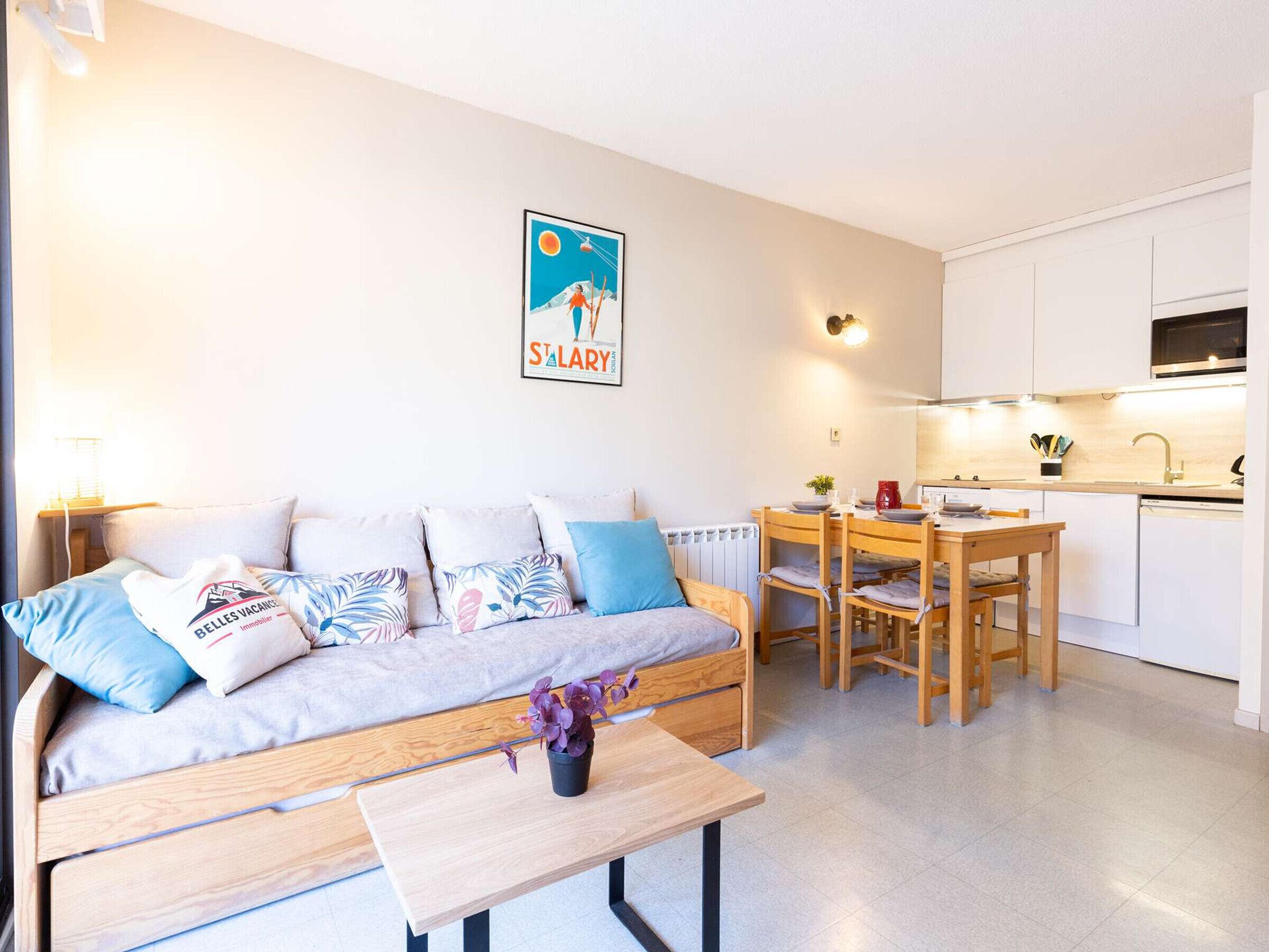 A modern, well-lit apartment with a sofa, a dining table, and a kitchen area.