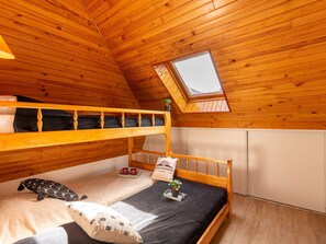 Un dormitorio acogedor en el ático, con paredes de madera y techo inclinado.