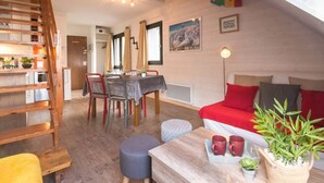 A cozy loft-style room with a dining area, a loft bed, and a staircase.