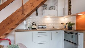 A modern kitchen with white cabinets, a built-in oven, and a coffee maker.