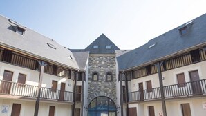 Ein Gebäude mit einem zentralen Eingang, einer steinernen Fassade und mehreren Balkonen.
