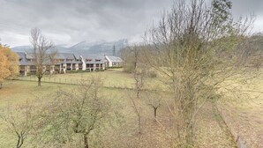 Ein Hotel mit mehreren Gebäuden, einer Wiese und einem Berg im Hintergrund.
