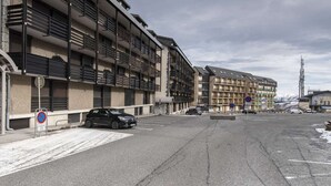 Un edificio de varios pisos con balcones, un área de estacionamiento y un letrero de no estacionar.
