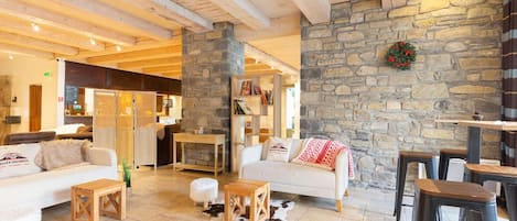 A cozy interior with a stone wall, wooden beams, a white sofa, and a bar area.
