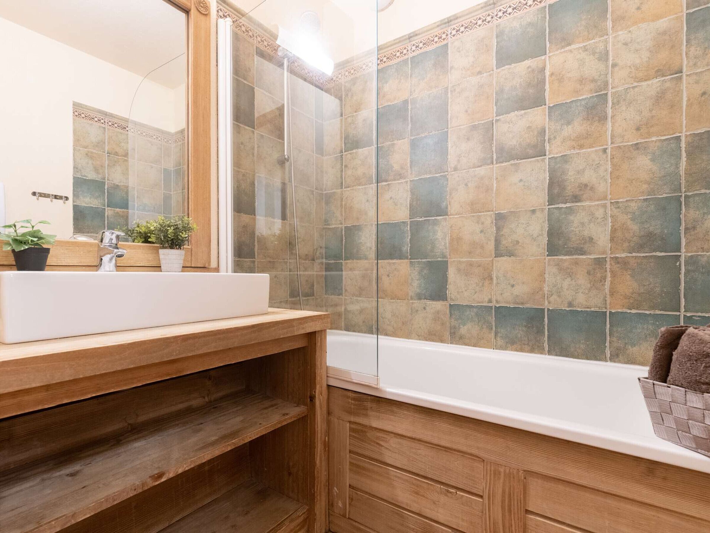 A bathroom with a white sink, wooden vanity, and a bathtub.