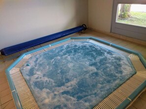 A hot tub in a room with a window and a blue mat.