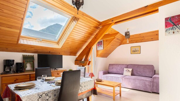A cozy room with a dining table, chairs, a sofa, and a television.