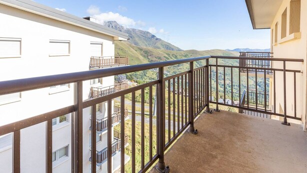 A balcony with a metal railing overlooking a mountainous landscape.