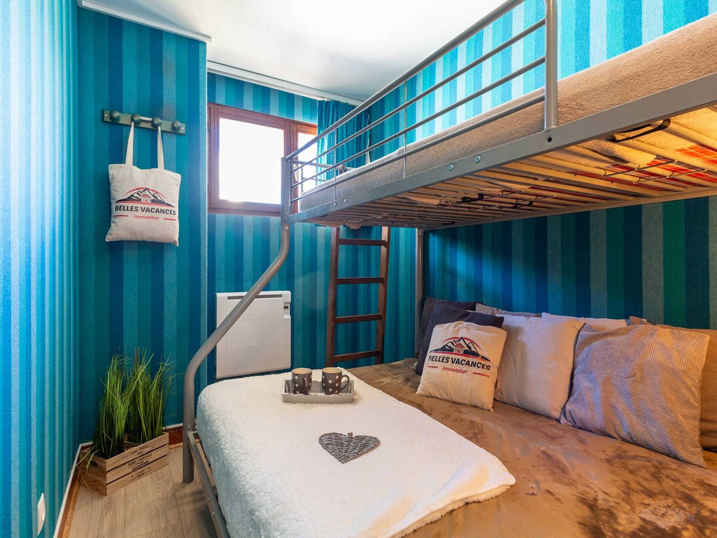 Une petite pièce avec un lit superposé, une petite table avec des tasses, un radiateur et une fenêtre.