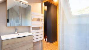 Un baño moderno con un espejo grande, tocador blanco y suelo de madera.