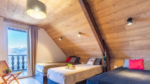 Acogedor dormitorio en ático con dos camas, un balcón y techo de madera.