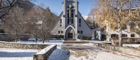 A church with a bell tower, stone walls, and a snow-covered courtyard.