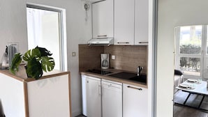 A compact kitchen with white cabinets, a coffee maker, and a dishwasher. - Apartment 4 ppl. Saint-Lary, Near center, WIFI (Saint-Lary-Soulan)