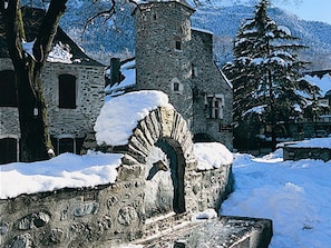 A stone building with a snow-covered archway and a small tower.