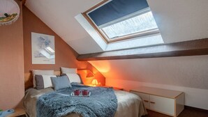 Um quarto com um clarabóia, uma cama com almofadas, uma mesa de cabeceira e um abajur.