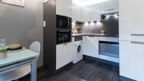 A compact kitchen with a microwave, oven, and washing machine. - Renovated apartment for 4, quiet, near Saint-Lary center (Saint-Lary-Soulan)