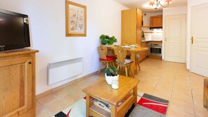 A compact living space with a TV, dining table, chairs, a small kitchen area, and a door. - 4-person apartment with pool and parking in Vielle Aure (Vielle-Aure)