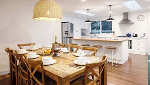 Een moderne keuken met witte kasten, een houten eettafel en een groot schiereiland.