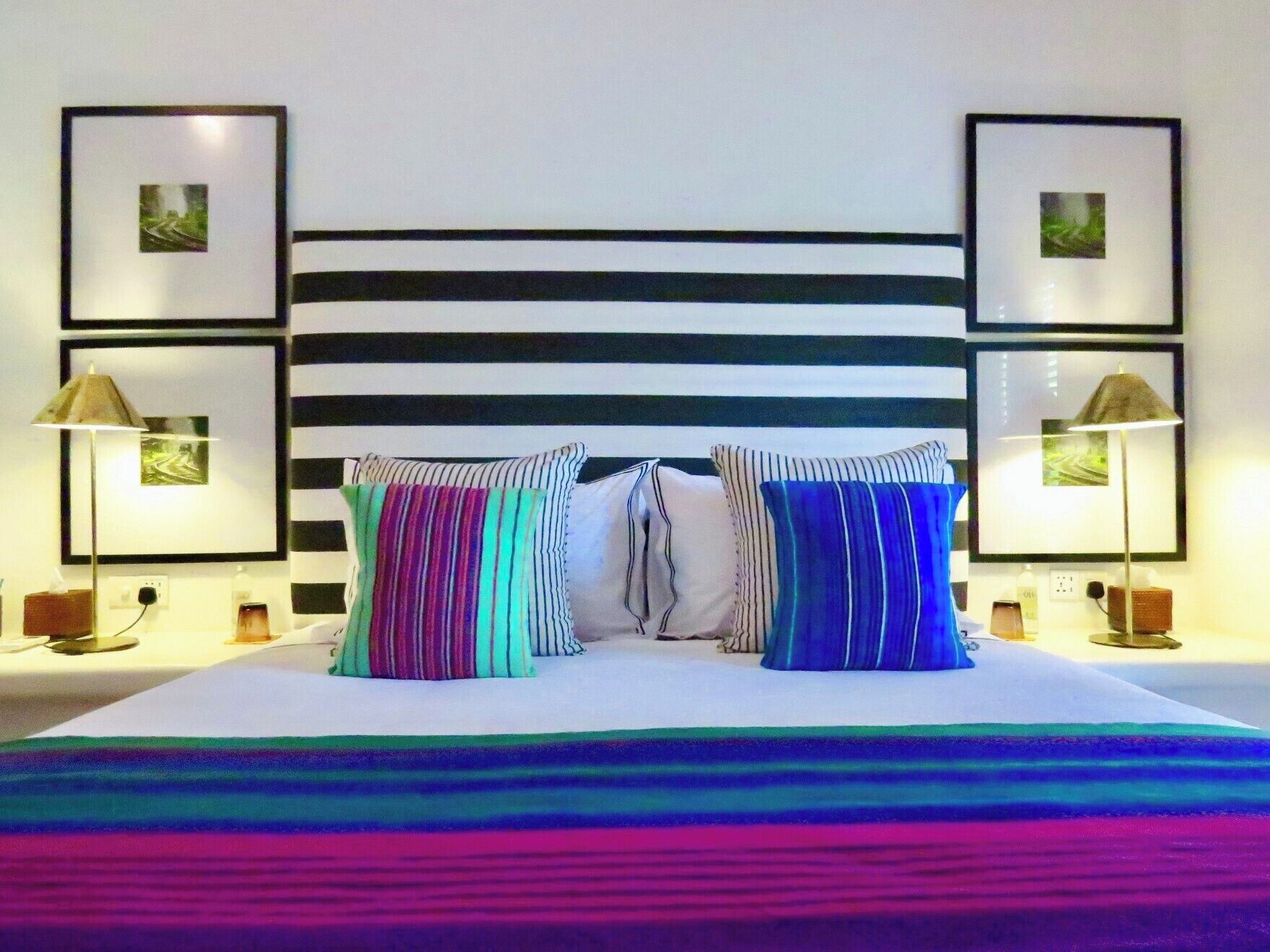 A bed with a striped headboard, two pillows, and a colorful blanket.