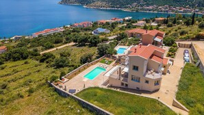 Propiedad costera con piscina, varias edificaciones y vistas al mar y a las montañas.