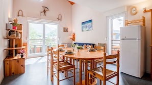 Une cuisine chaleureuse avec une table ronde en bois, des chaises en bois et un réfrigérateur blanc.