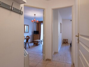 A hallway with a dining area, a television, and a chandelier.