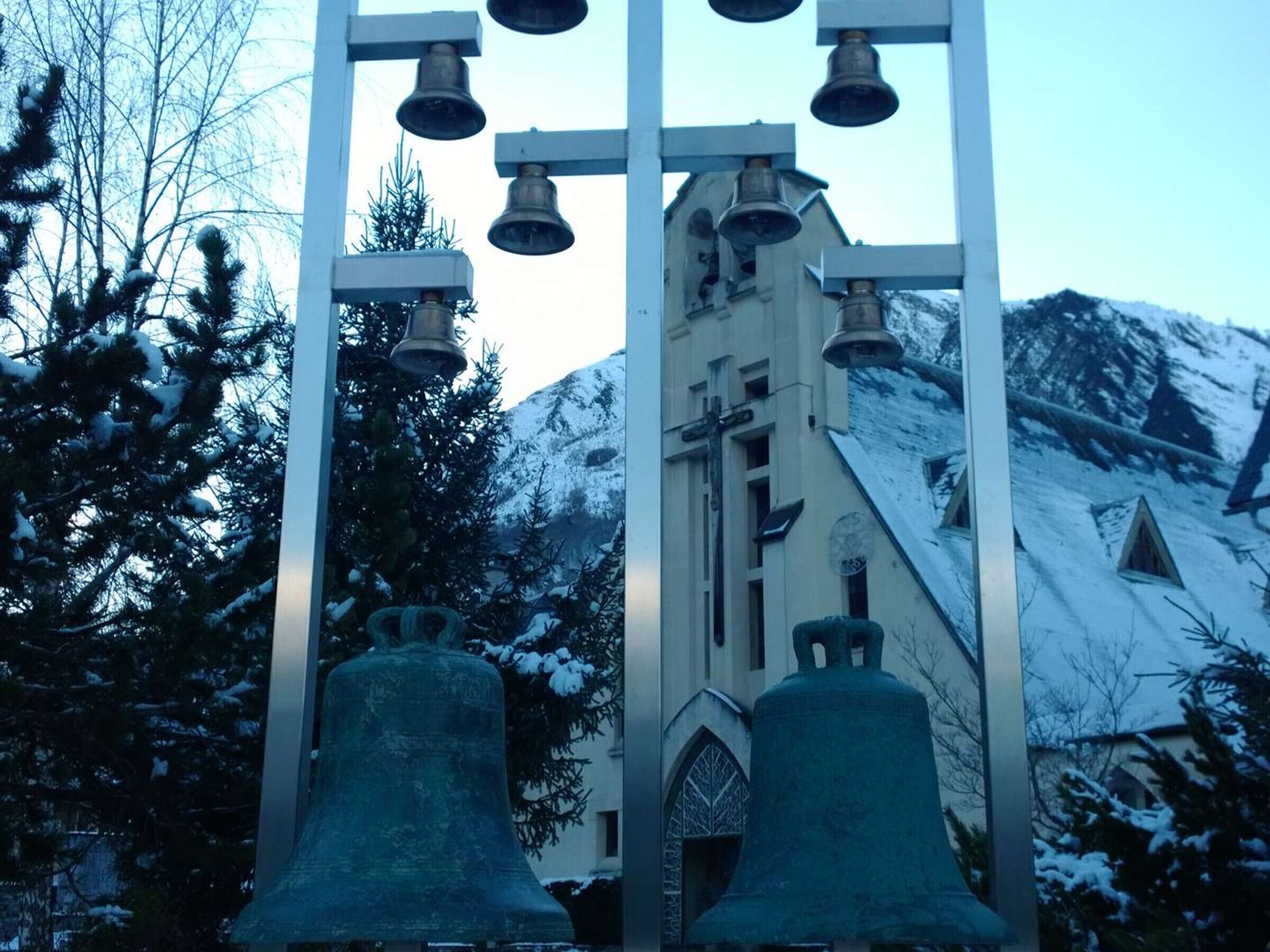 A church with a bell tower and snow-covered trees.