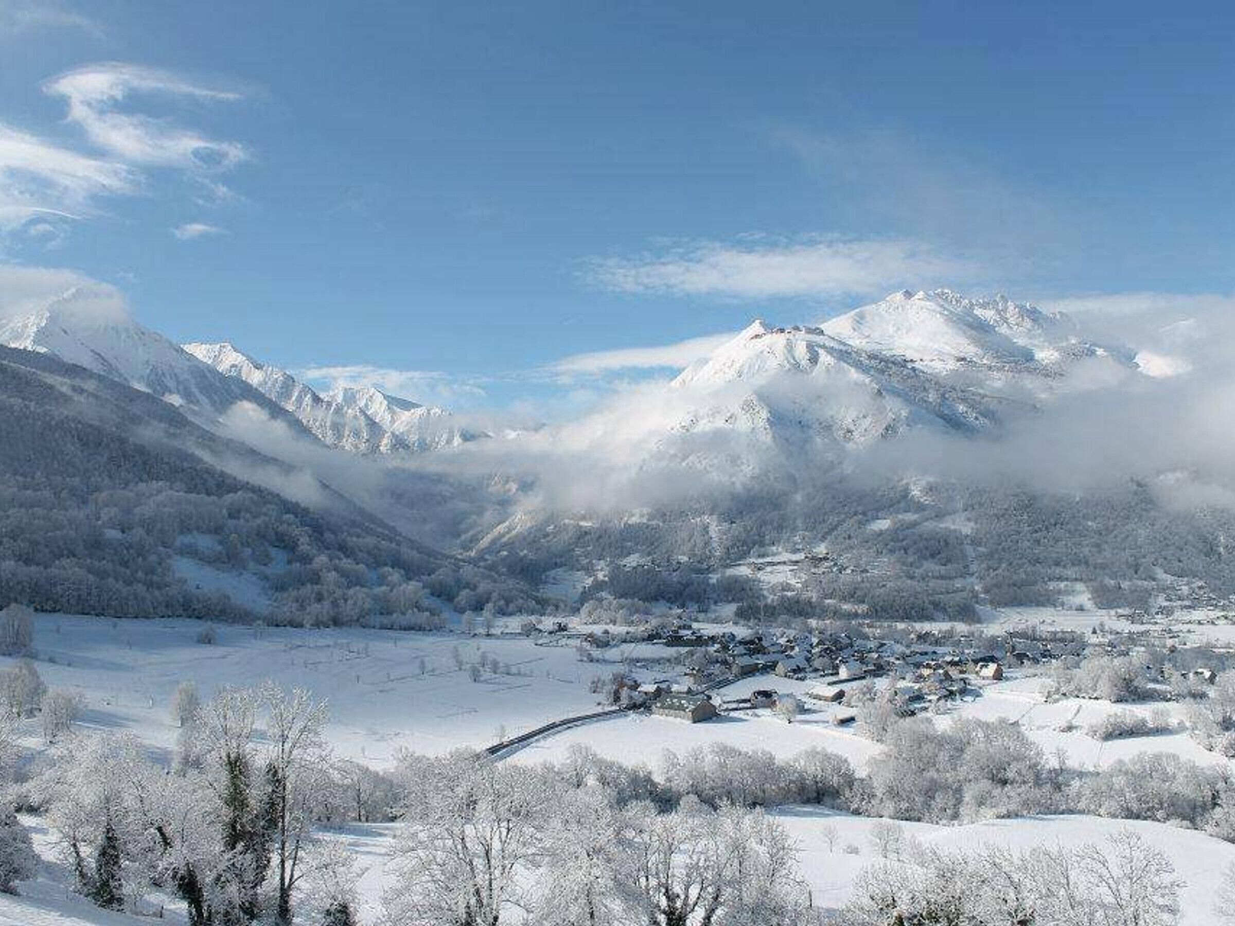 Paesaggio montuoso innevato con un piccolo villaggio nascosto nella valle.