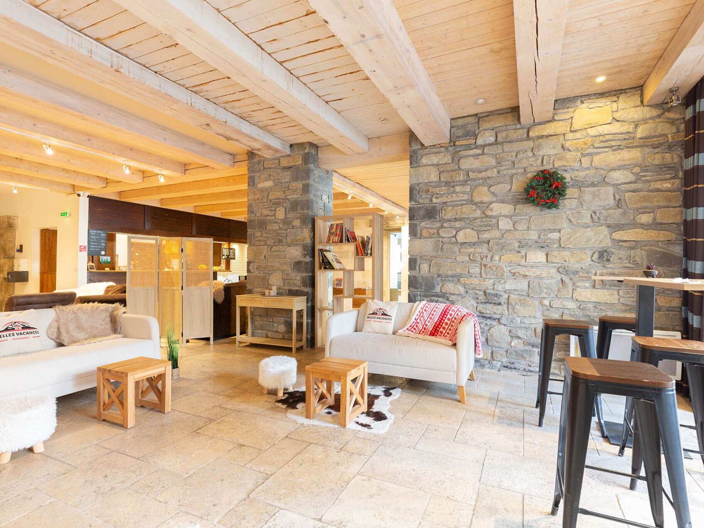 A cozy interior with a stone wall, wooden beams, a white sofa, and a bar area.