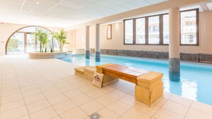 An indoor swimming pool with clear blue water, tiled floor, and large windows. - Duplex Apartment for 8 with Pool and Sauna in City Center (Saint-Lary-Soulan)