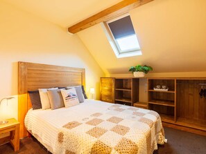 A cozy bedroom with a wooden headboard, a checkered quilt, a skylight, and built-in wooden shelves. - Duplex Apartment for 8 with Pool and Sauna in City Center (Saint-Lary-Soulan)